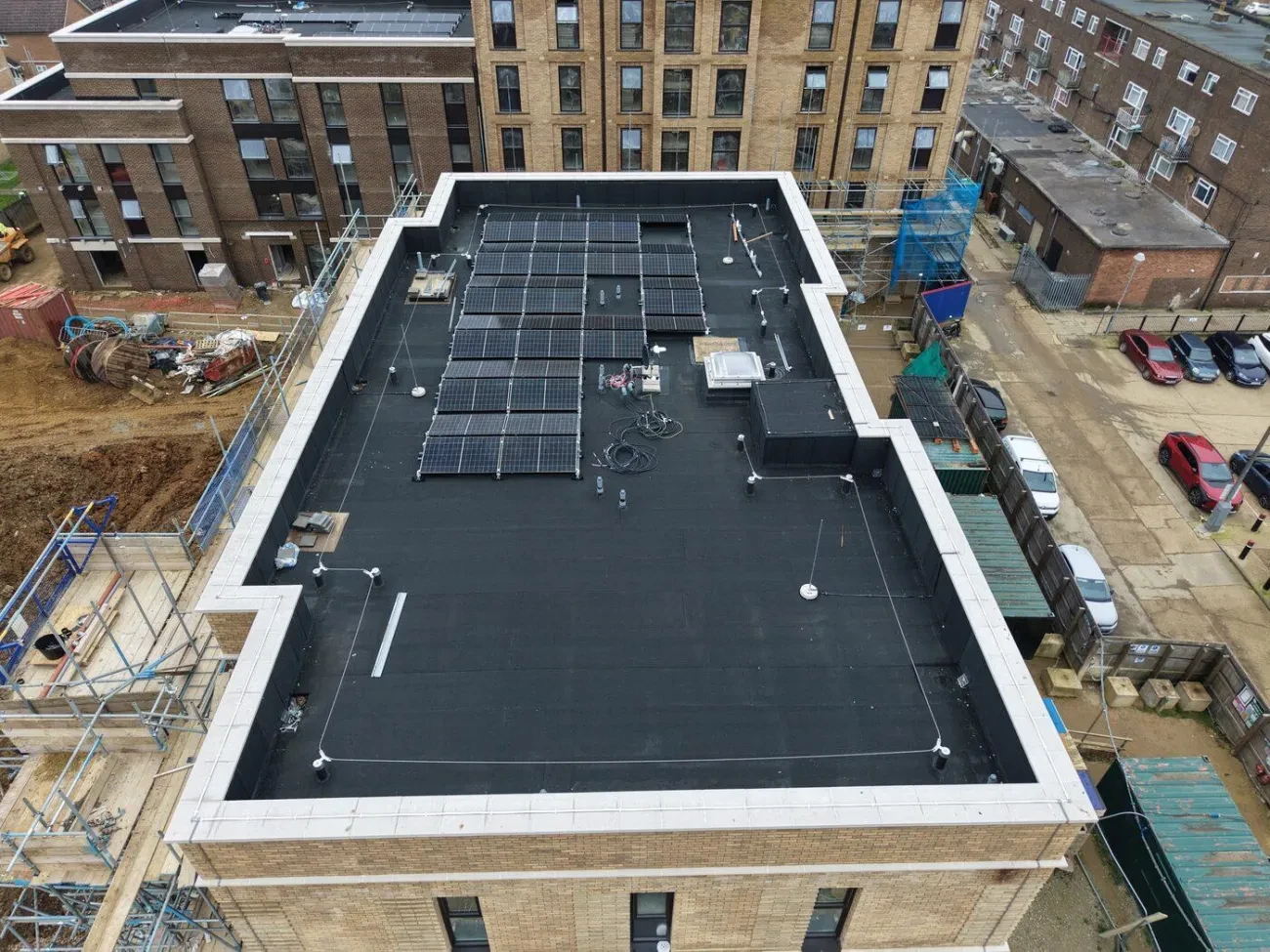 Block flat roof – MOY Paralon charcoal grey membrane, man safe cable runs and solar PV installation visible.