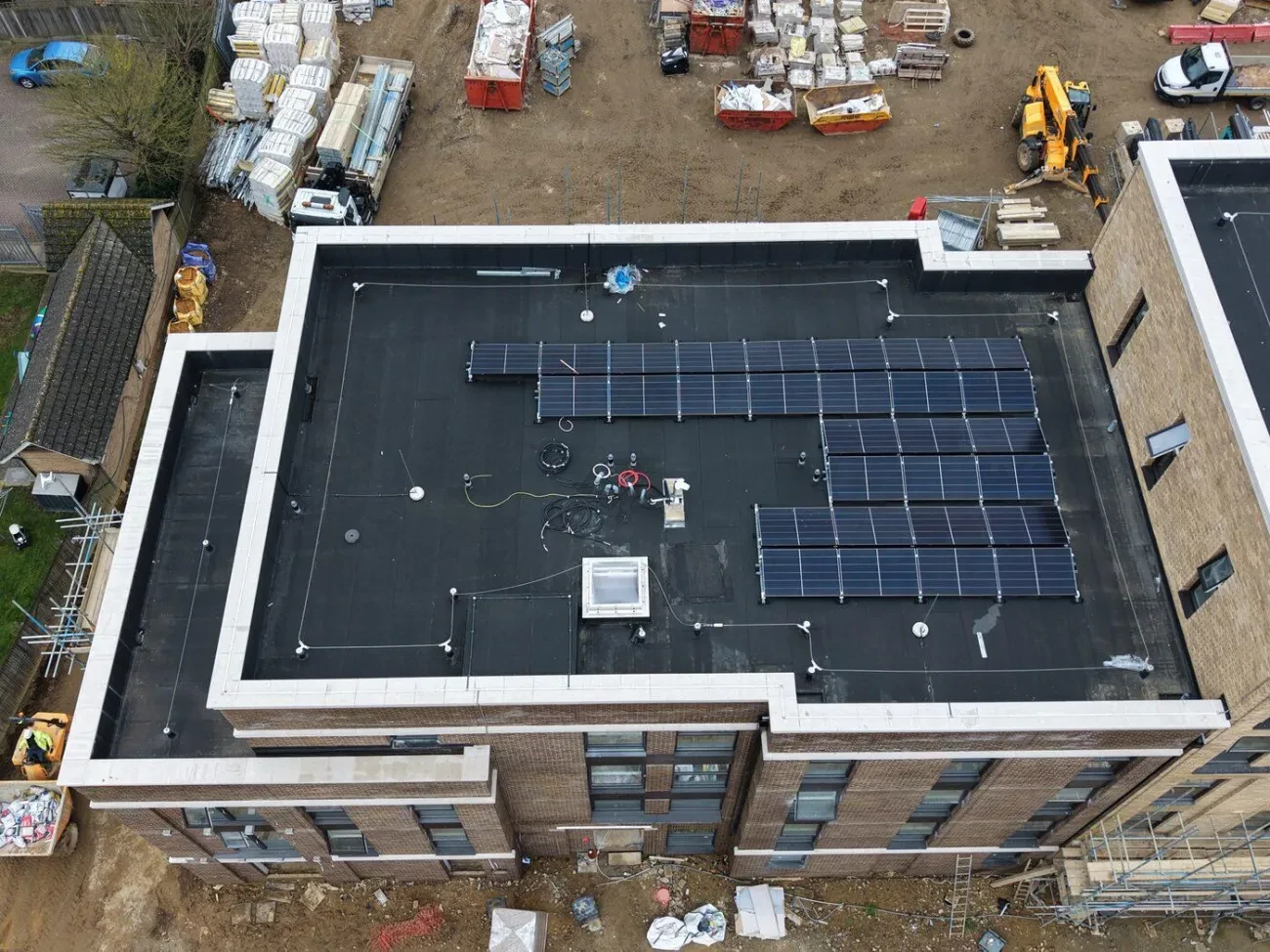 Flat roof with solar PV array and Bettersafe Roof Angel horizontal lifeline installed – man safe posts visible around perimeter.