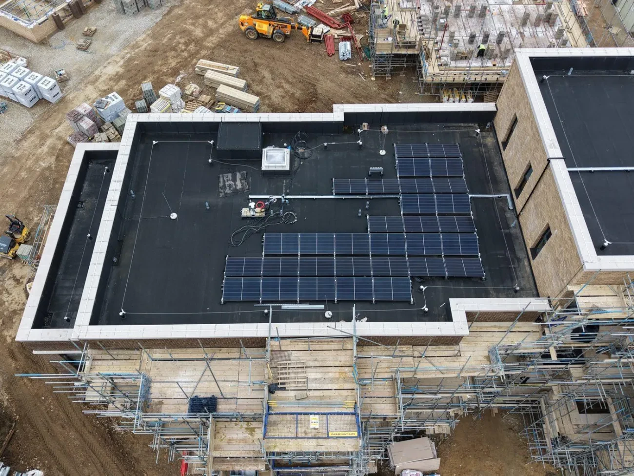 Flat roof during construction – mansafe posts, cable runs and solar PV array being installed across one of the Cambridge Crescent apartment blocks.