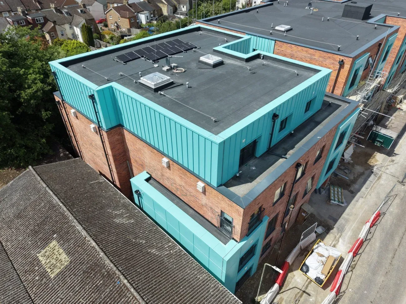 West elevation — teal cladding & lower roofs