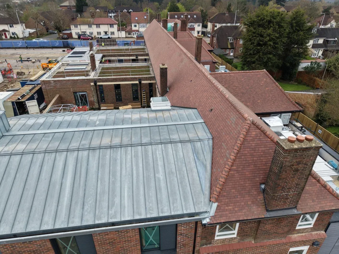 Close-up of the zinc standing seam link roof adjacent to the re-tiled main building, showing the junction between old and new.