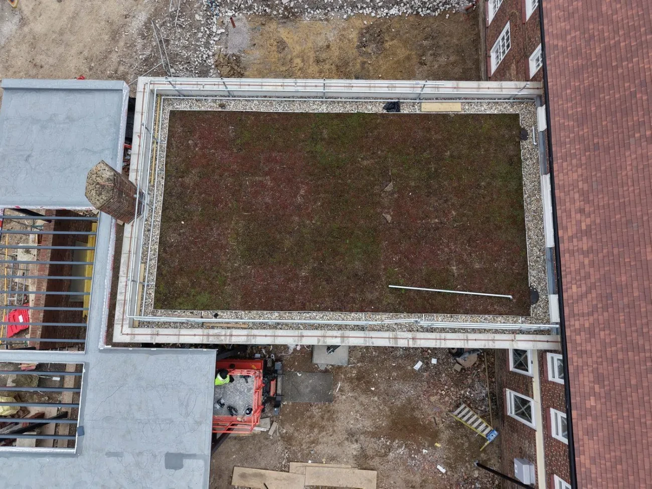 Close overhead view of completed sedum blanket green roof with washed pebble perimeter vegetation break and aluminium edge trim.