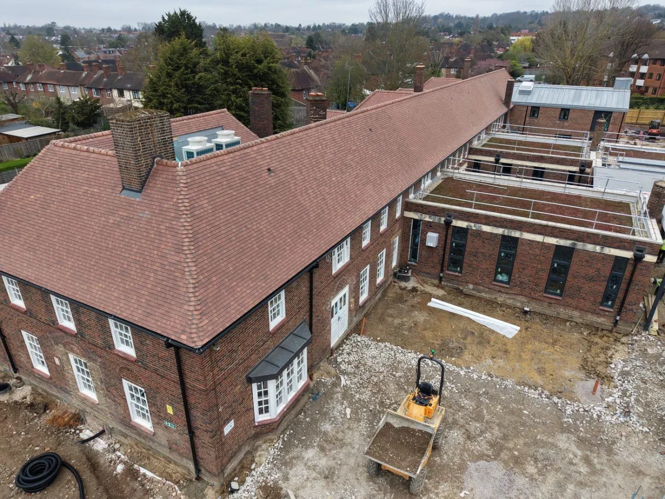 Elevation view of the south-facing main building showing the full length of the re-tiled roof, hips, ridges and original brick chimneys.