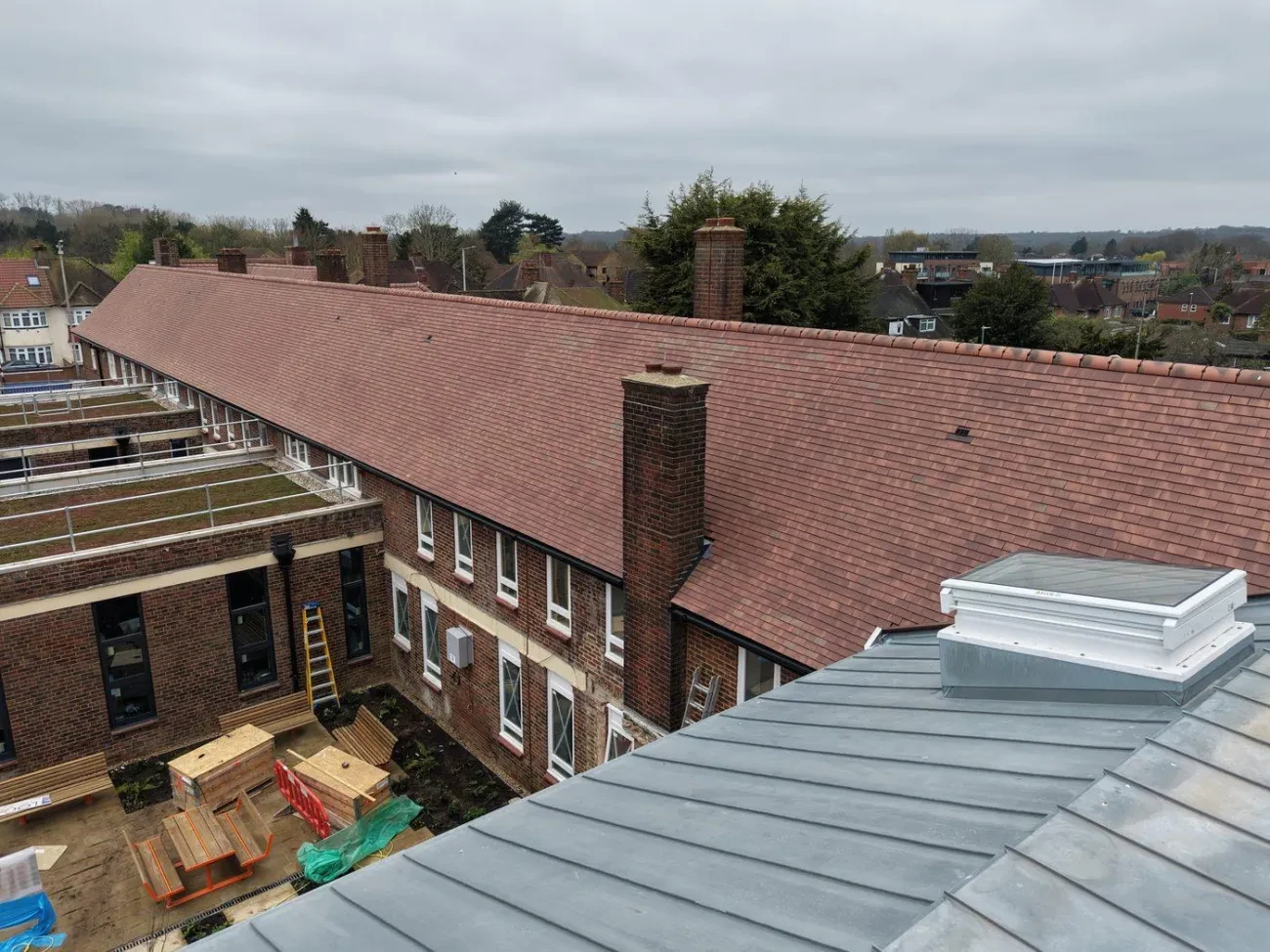 View showing the main building pitched roof alongside the new zinc-clad link and sedum green roof areas on the extension.